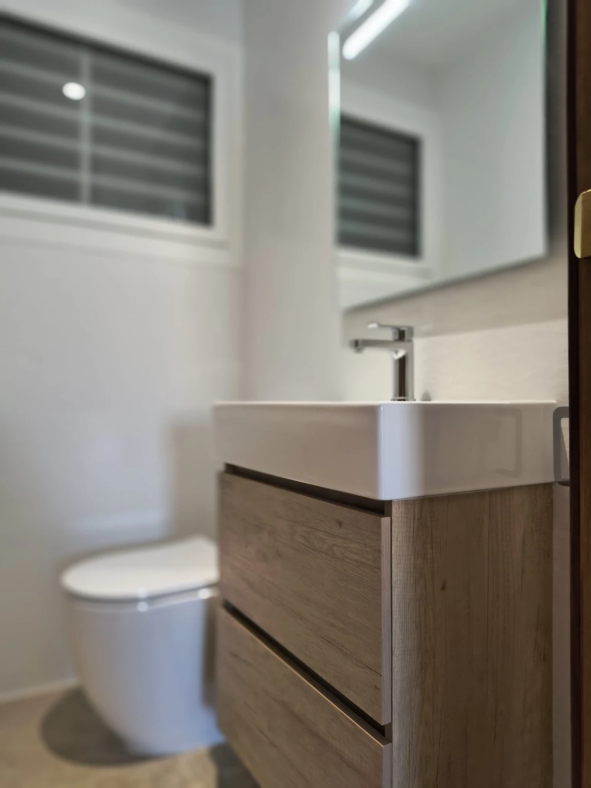 Detalle de mueble de baño, lavabo y sanitario en reforma terminada por URMA MC Reformas